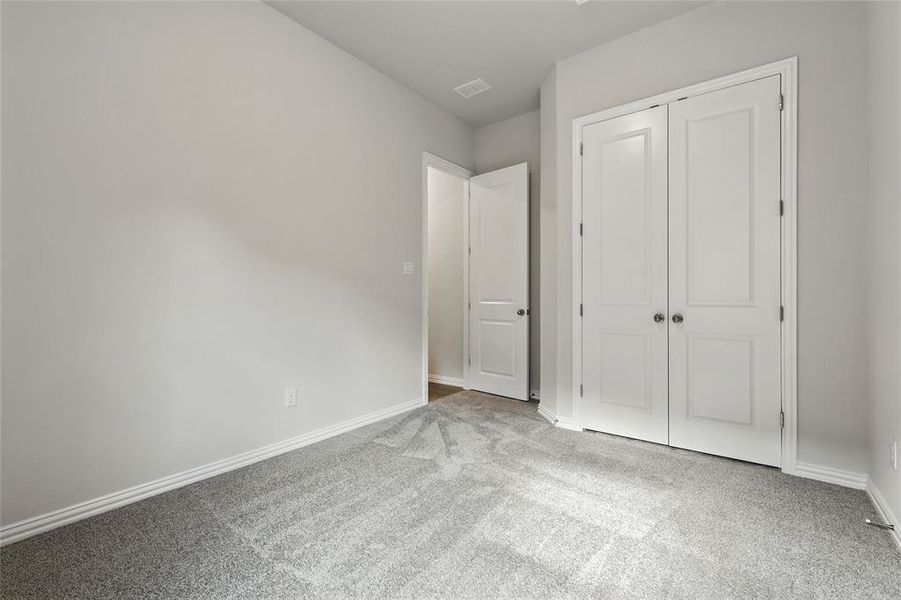 Unfurnished bedroom with light colored carpet and a closet