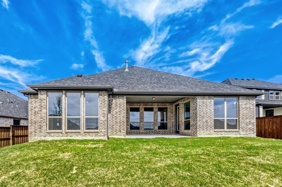 Rear view of house featuring a fenced backyard, brick siding, and a patio area