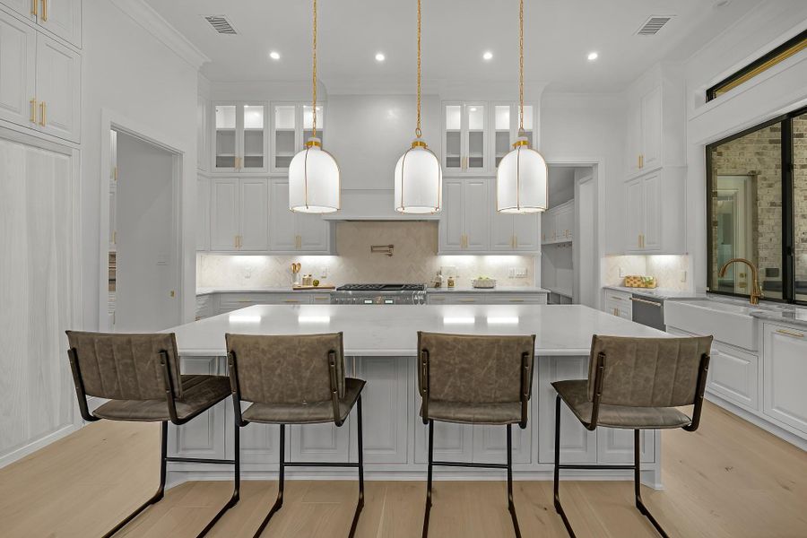 This light and bright kitchen features a large quartz island, white cabinets, a large sink overlooking your family room, recessed lighting, and beautiful backsplash. Photo may be virtually staged This light and bright kitchen features a large quartz island, white cabinets, a large sink overlooking your family room, recessed lighting, and beautiful backsplash. Photo may be virtually staged