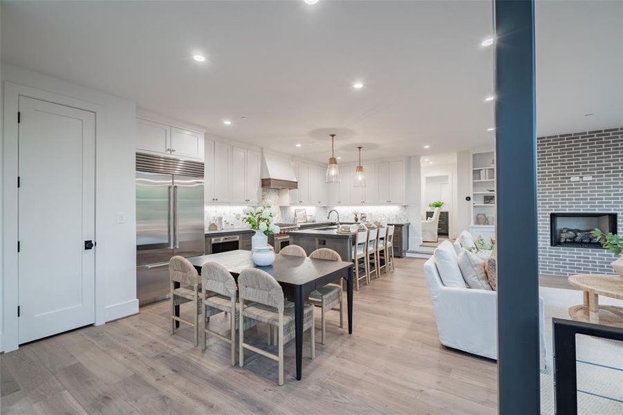 Kitchen featuring sink, stainless steel dishwasher, an island with sink, light hardwood / wood-style floors, and decorative light fixtures