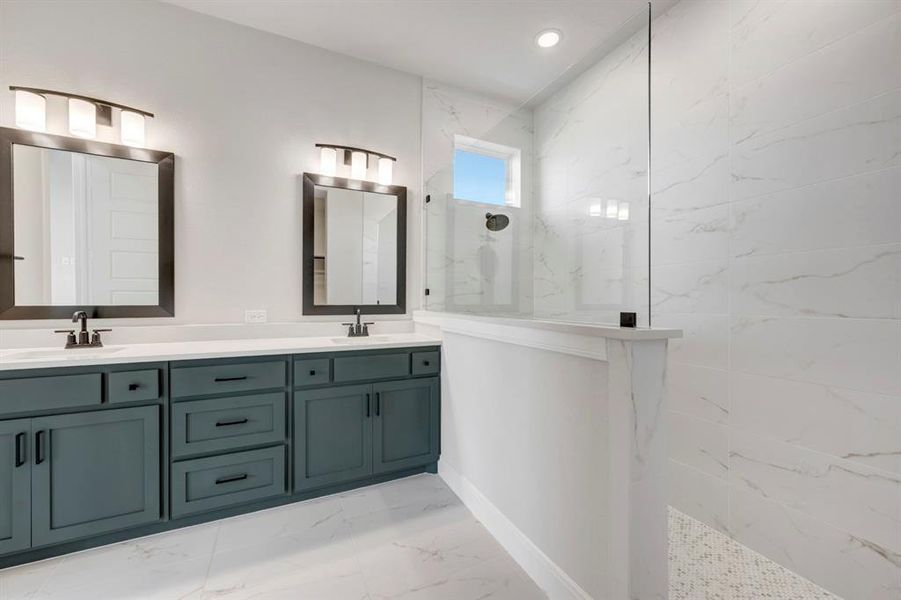 Bathroom featuring a marble finish shower, double vanity, light marble finish floors, and recessed lighting