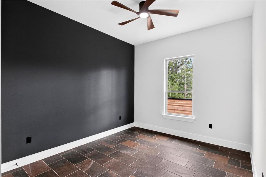 Spare room featuring stone tile floors and a ceiling fan Spare room featuring stone tile floors and a ceiling fan
