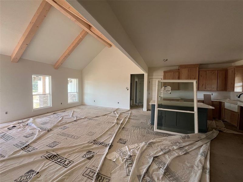 Kitchen featuring high vaulted ceiling, sink, light carpet, and beam ceiling