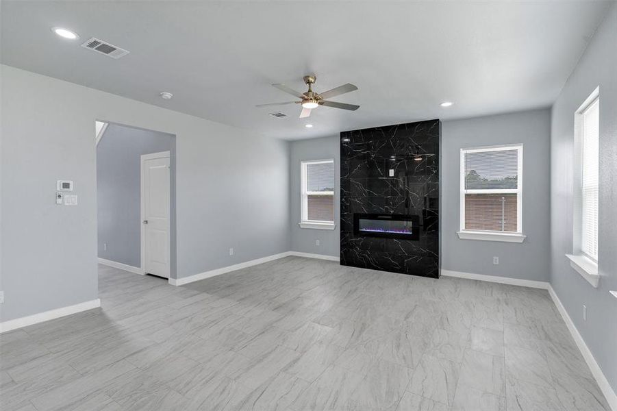 Unfurnished living room featuring a high end fireplace, a ceiling fan, and recessed lighting