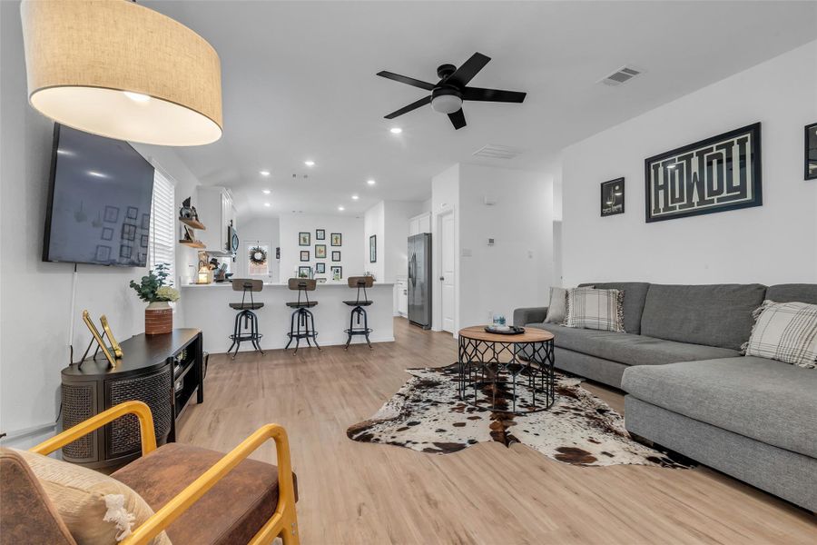 This light and bright family room has lots of windows to let in the natural light, can lights for task lighting, and a ceiling fan to circulate the air. To the right of the couch is the hallway that leads to the full bathroom, storage closet, and two bedrooms.