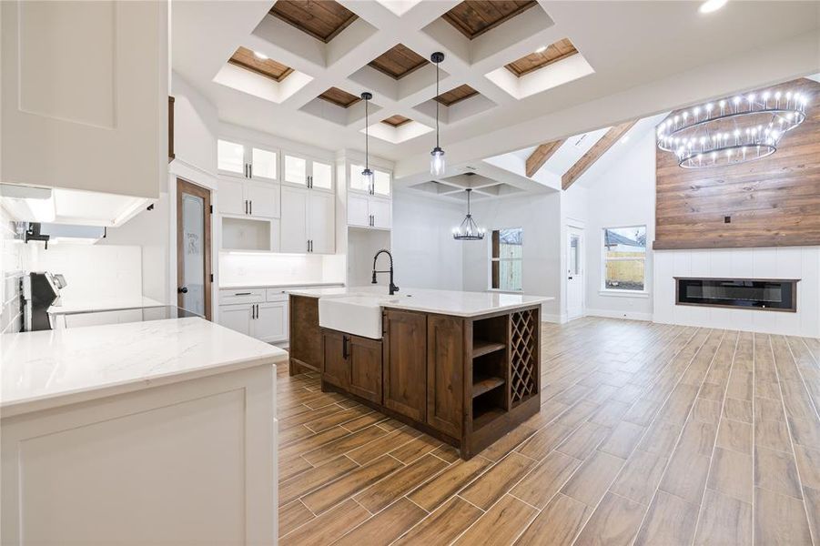 Kitchen featuring sink, an island with sink, white cabinets, pendant lighting, and a high ceiling