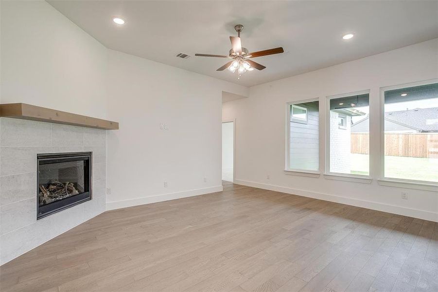 Unfurnished living room with ceiling fan, light hardwood / wood-style flooring, and a tile fireplace