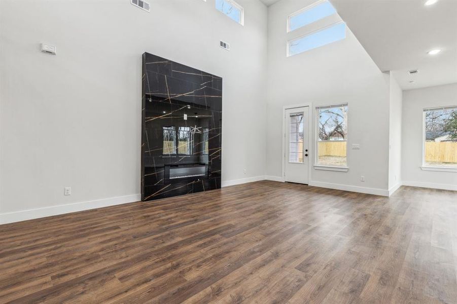 Unfurnished living room featuring dark hardwood / wood-style floors and a towering ceiling