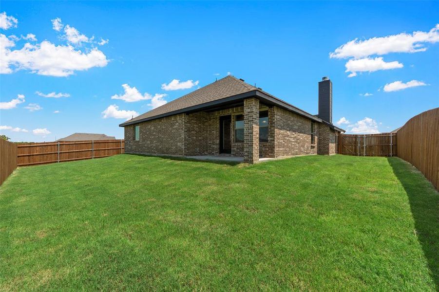 Rear view of house featuring brick siding, a chimney, a fenced backyard, and a patio area