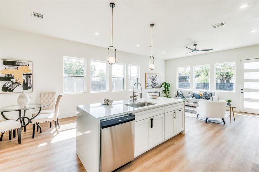 Kitchen with a wealth of natural light, a center island with sink, sink, and stainless steel dishwasher