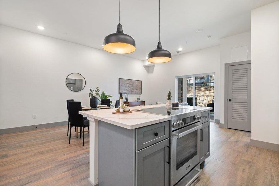 Kitchen with high end stainless steel range oven, pendant lighting, gray cabinets, a center island, and light wood-style flooring