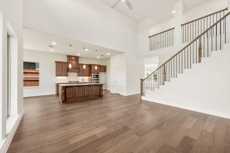 Open living area with hardwood floors, kitchen island, dark wood cabinets, and staircase with iron balusters Open living area with hardwood floors, kitchen island, dark wood cabinets, and staircase with iron balusters