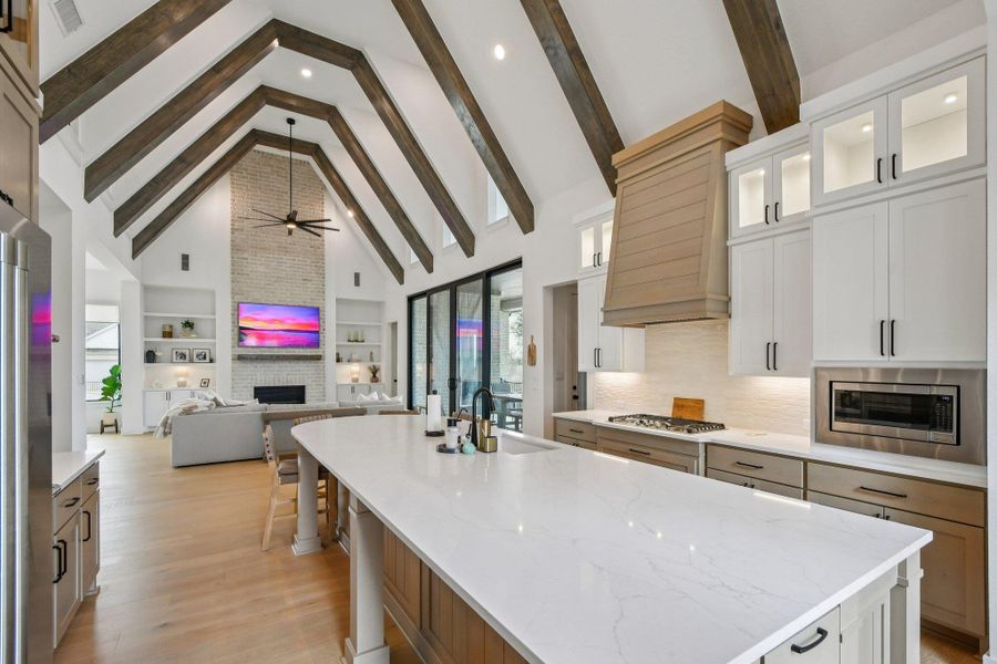 Open concept living space featuring a kitchen with a large central island, white countertops, and a gas range Open concept living space featuring a kitchen with a large central island, white countertops, and a gas range