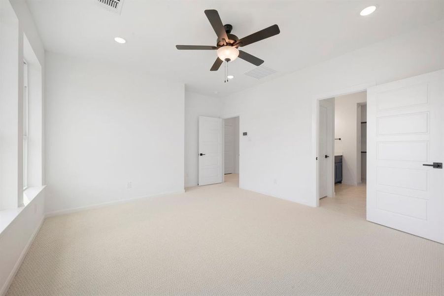 Spacious room featuring light-colored carpet, white walls, and a ceiling fan with integrated lighting