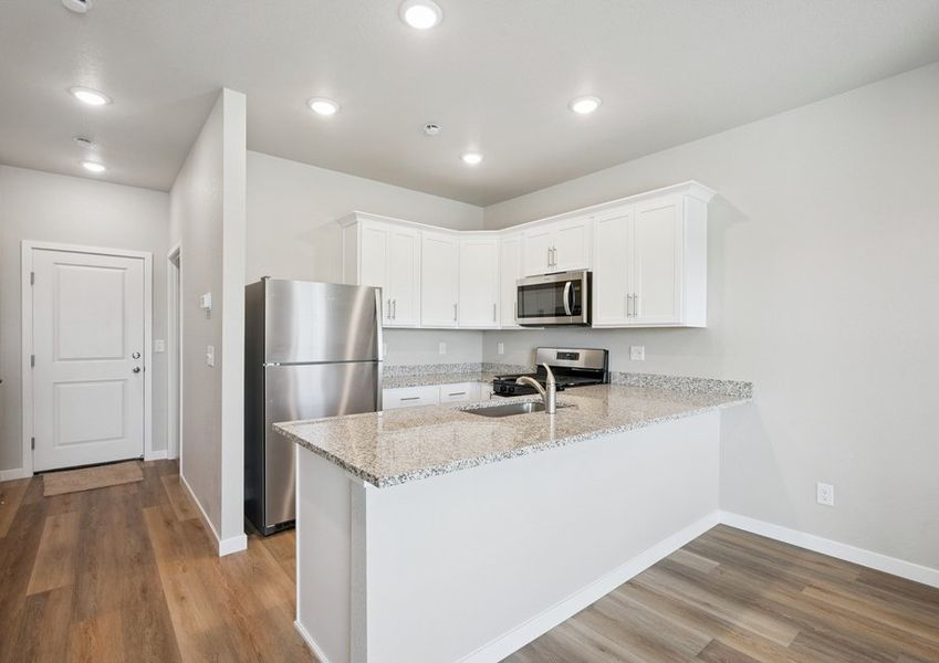 The kitchen has stainless steel appliances and plank flooring.