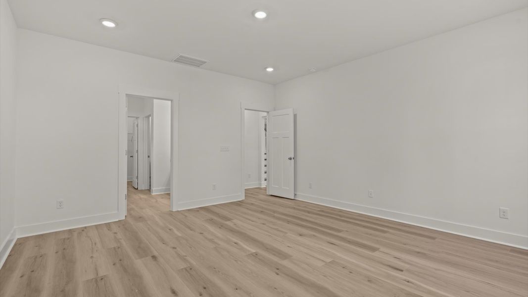 Superior design meets vibrant comfort in this primary suite with hardwood floors and walk-in closet