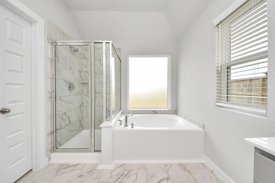 This additional view of the primary bath features a walk-in shower with the tile surround and separate garden tub perfect for soaking after a long day.