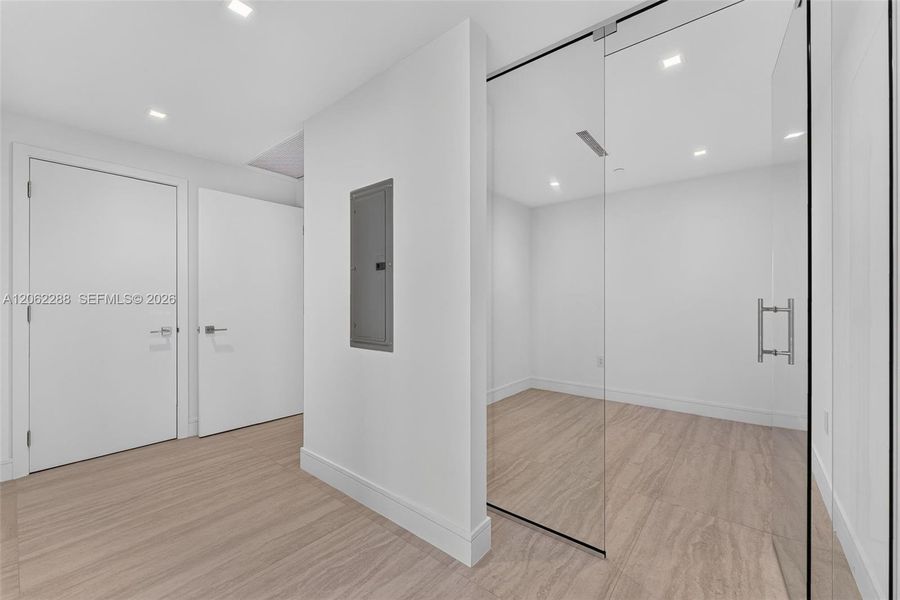 Enclosed room featuring a floor-to-ceiling glass partition, wood-finish flooring, recessed lighting, and solid-core interior doors