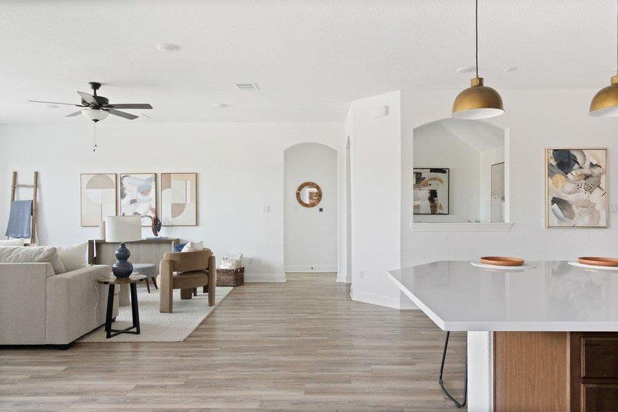 Living area featuring arched walkways, light wood-type flooring, and a ceiling fan Living area featuring arched walkways, light wood-type flooring, and a ceiling fan