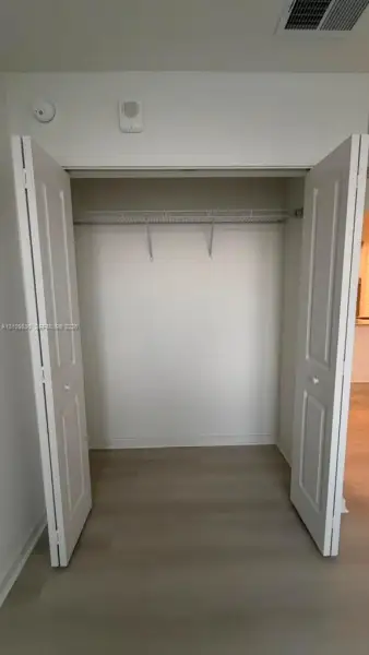 Closet featuring white bi-fold doors, interior wire shelving, and wood-finish flooring