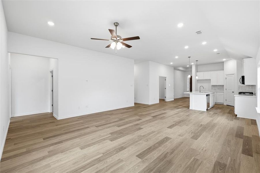 Open-concept living space featuring wood-finish flooring, recessed lighting, and a ceiling fan