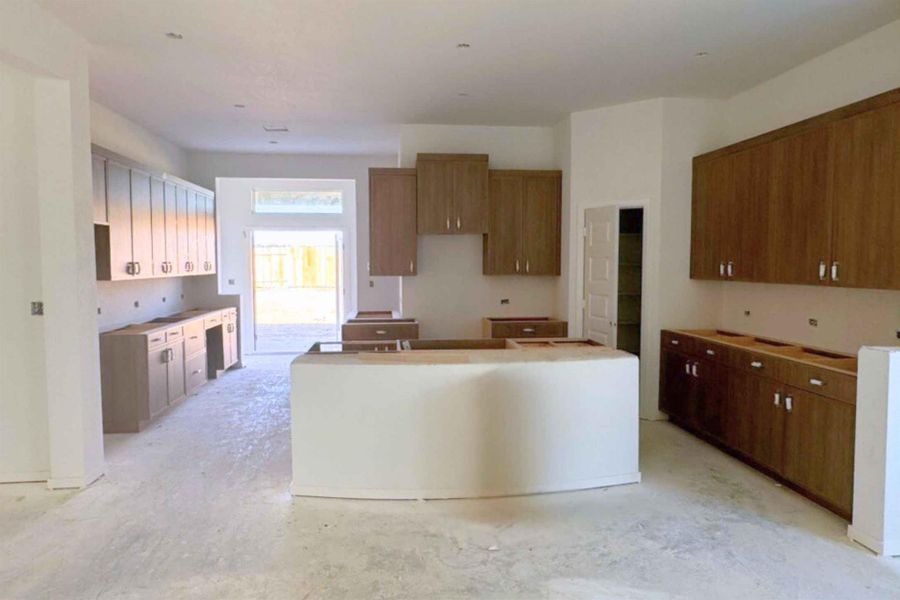Kitchen with a kitchen island, brown cabinetry, and unfinished concrete floors Kitchen with a kitchen island, brown cabinetry, and unfinished concrete floors