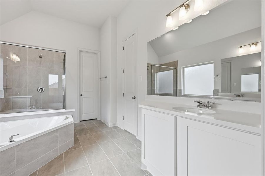 Full bathroom featuring vanity, a bath, a tile shower, light tile patterned floors, and vaulted ceiling Full bathroom featuring vanity, a bath, a tile shower, light tile patterned floors, and vaulted ceiling