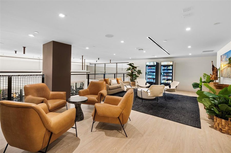 Open-concept lounge featuring wood-finish flooring, recessed lighting, and a metal-grid balcony railing