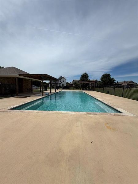 Rectangular swimming pool with a surrounding  black metal fence
