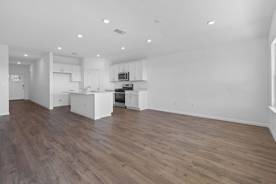 Kitchen featuring open floor plan, white cabinetry, dark wood-type flooring, appliances with stainless steel finishes, and recessed lighting