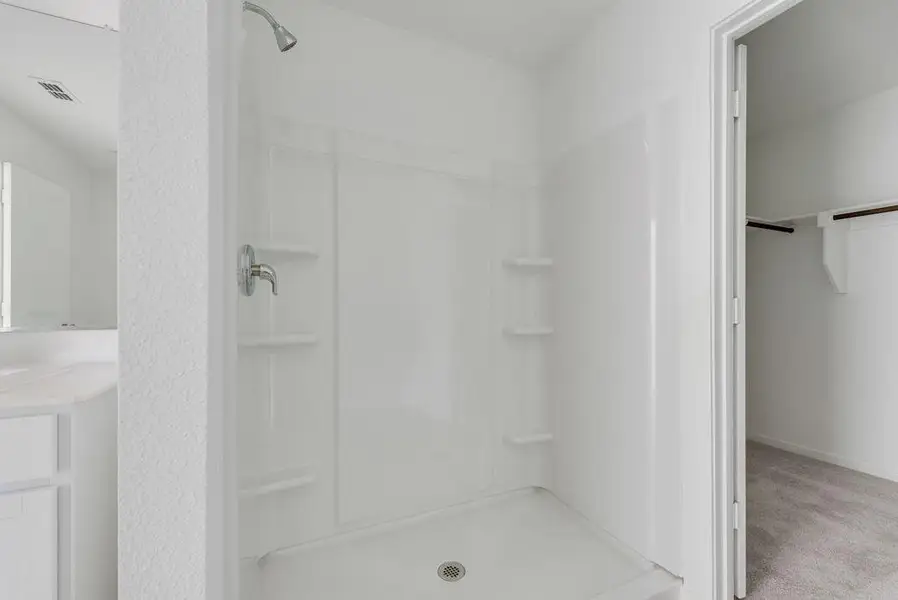 Full bath with a stall shower, vanity, and a walk in closet Full bath with a stall shower, vanity, and a walk in closet
