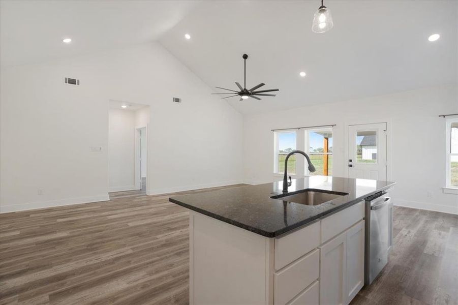 Kitchen with open floor plan, white cabinets, recessed lighting, dark  countertops, and wood-style floors
