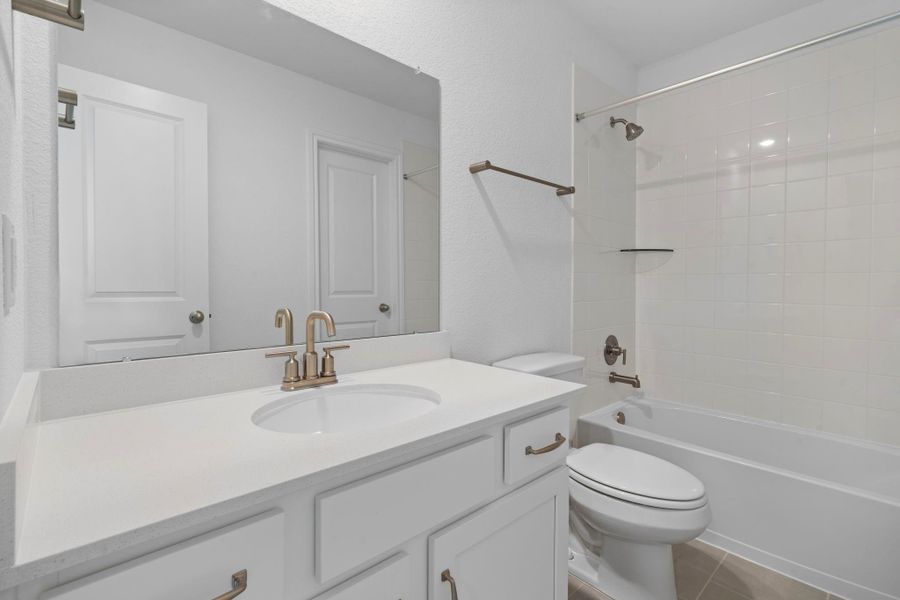 The secondary bath features tile flooring, white cabinetry and light countertops and a shower/tub combo. Perfect for accommodating any visiting family and friends.