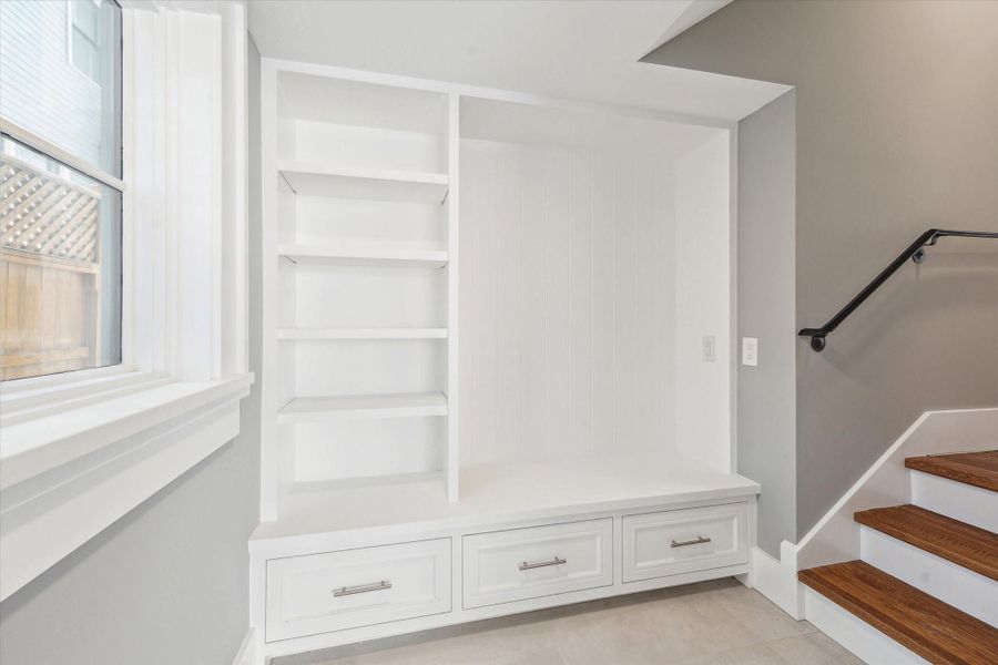 This is the back entrance from the garage and has a built-in white bench with storage drawers and shelves, located next to a window--ideal for leaving  backpack, etc before you enter the house.