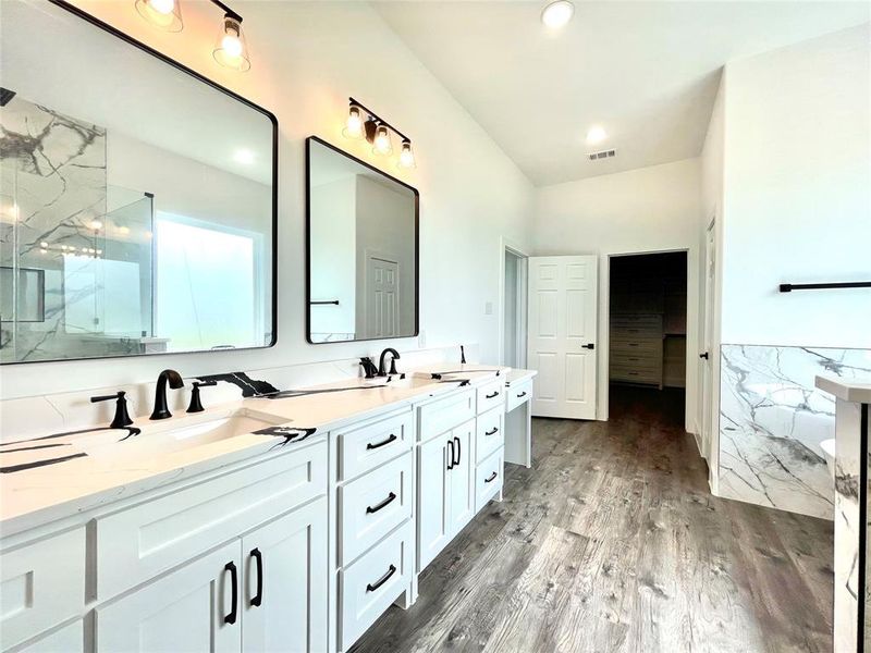 Full bath with double vanity, wood finished floors, a marble finish shower, and a sink Full bath with double vanity, wood finished floors, a marble finish shower, and a sink