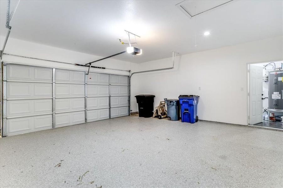 Spacious garage featuring a two-car overhead door, light-colored speckled flooring, and white painted walls