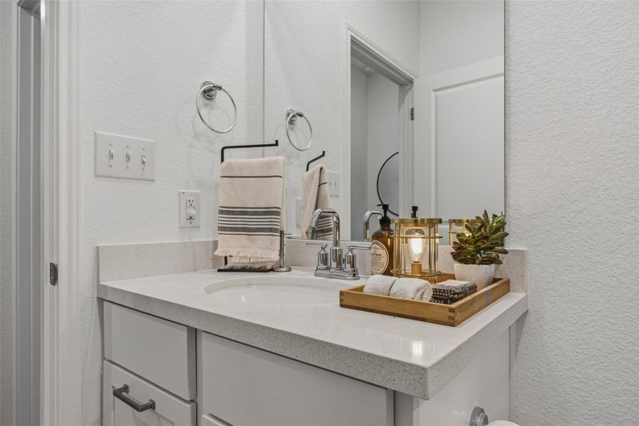 Bathroom vanity featuring a single basin sink, light-toned countertop, and chrome faucet