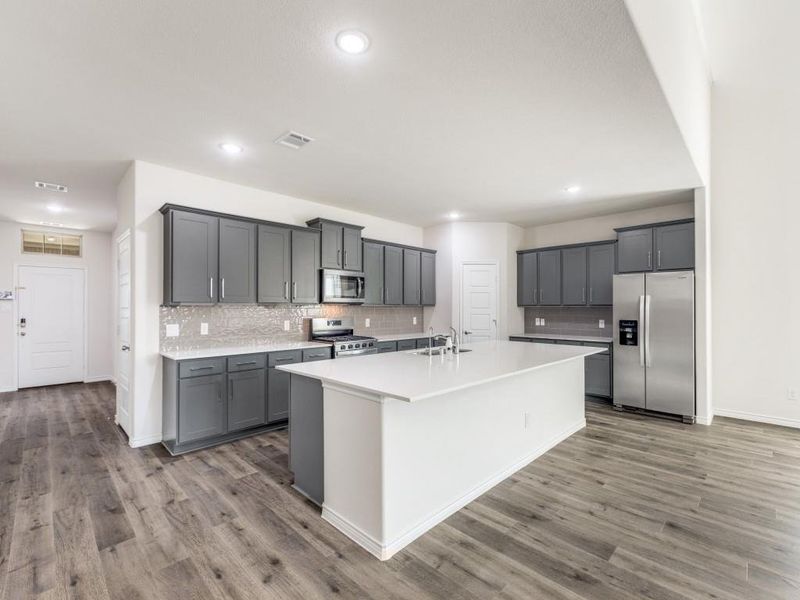 Kitchen with appliances with stainless steel finishes, tasteful backsplash, gray cabinetry, an island with sink, and recessed lighting