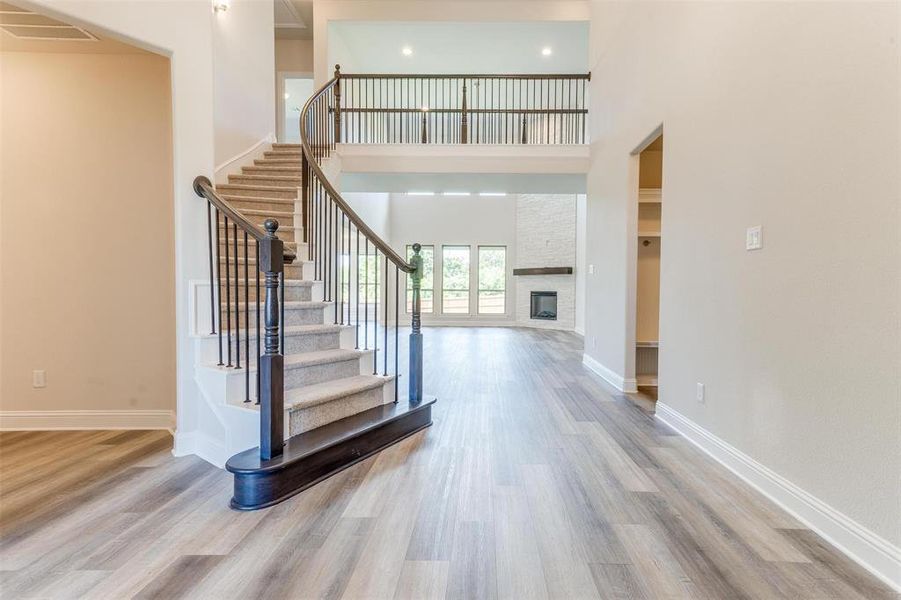 Stairs featuring a high ceiling, wood-type flooring, and a fireplace