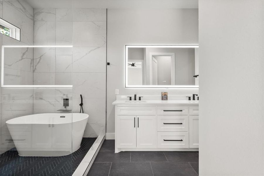 Bathroom with double vanity, a soaking tub, tile walls, and dark tile patterned flooring Bathroom with double vanity, a soaking tub, tile walls, and dark tile patterned flooring