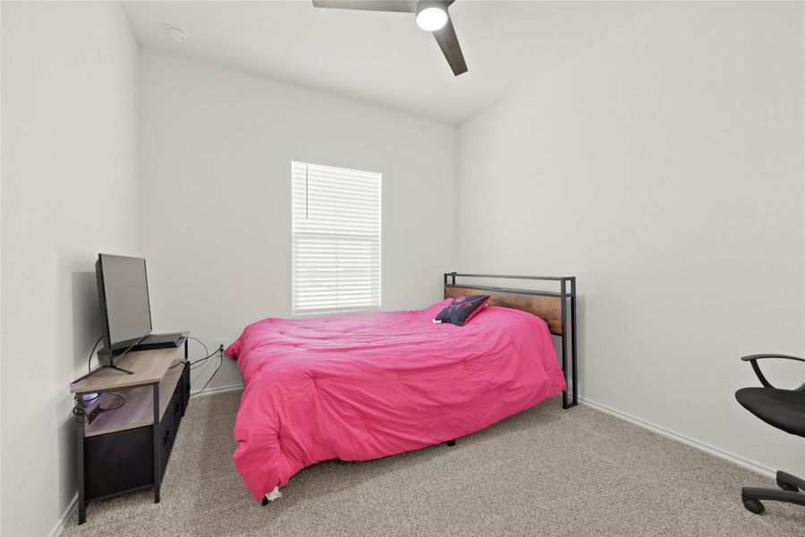 This main-floor bedroom offers a quiet retreat with plush carpeting and plenty of natural light, perfect for a guest room or a home office.
