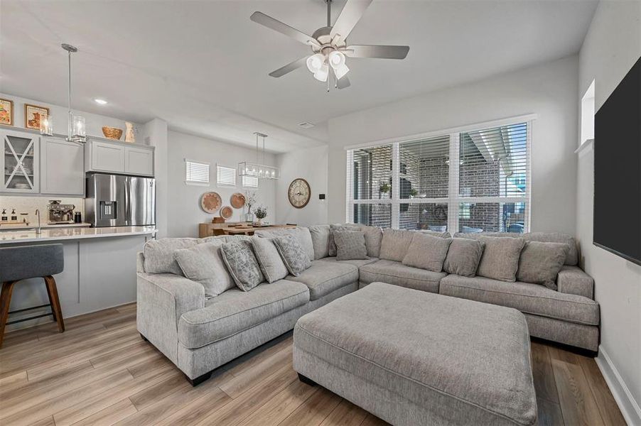 Living room featuring a ceiling fan, light wood finished floors, recessed lighting, and a chandelier Living room featuring a ceiling fan, light wood finished floors, recessed lighting, and a chandelier