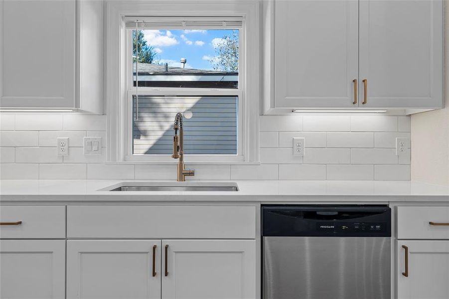 Kitchen with dishwasher, white cabinets, light stone counters, and backsplash Kitchen with dishwasher, white cabinets, light stone counters, and backsplash
