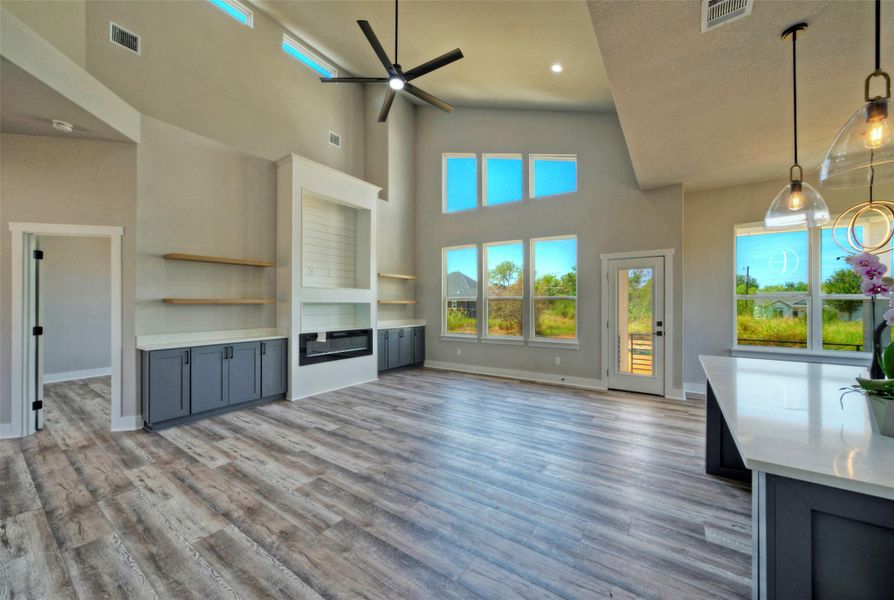 High vaulted ceilings and wood-style flooring elevate this modern living space with integrated built-ins. High vaulted ceilings and wood-style flooring elevate this modern living space with integrated built-ins.