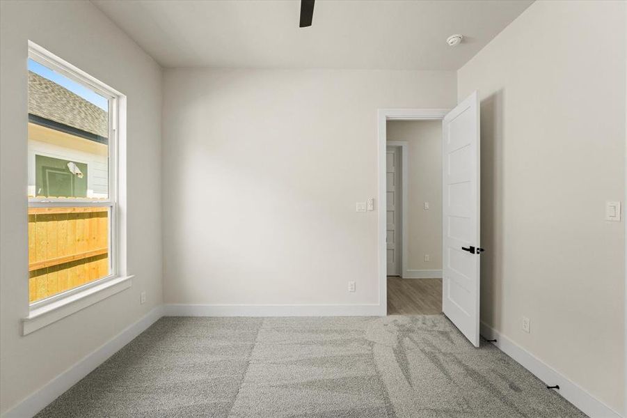 Empty room featuring light colored carpet and ceiling fan Empty room featuring light colored carpet and ceiling fan
