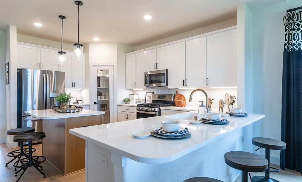 What a wonderful kitchen to gather in! This spacious open concept design features a large center island with seating, ample counter space, and a bright layout that flows beautifully into the living areas, complemented by stunning wood looking tile flooring throughout the main living areas, perfect for everyday living and easy entertaining. **Photos are representative only and may vary as built.**