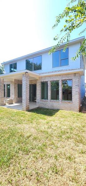 Back of property featuring a lawn and a patio area