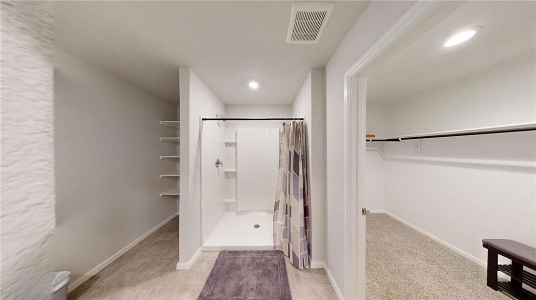 Bathroom with walk-in shower featuring a single shower head and built-in shelving