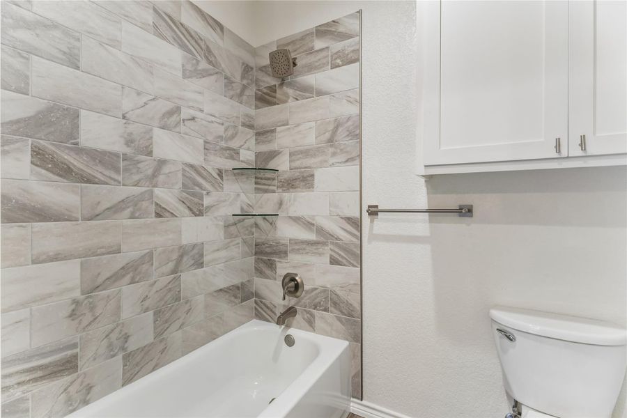 A well-appointed bathroom offers a clean tub-shower combination with elegant tile work and practical shelving.