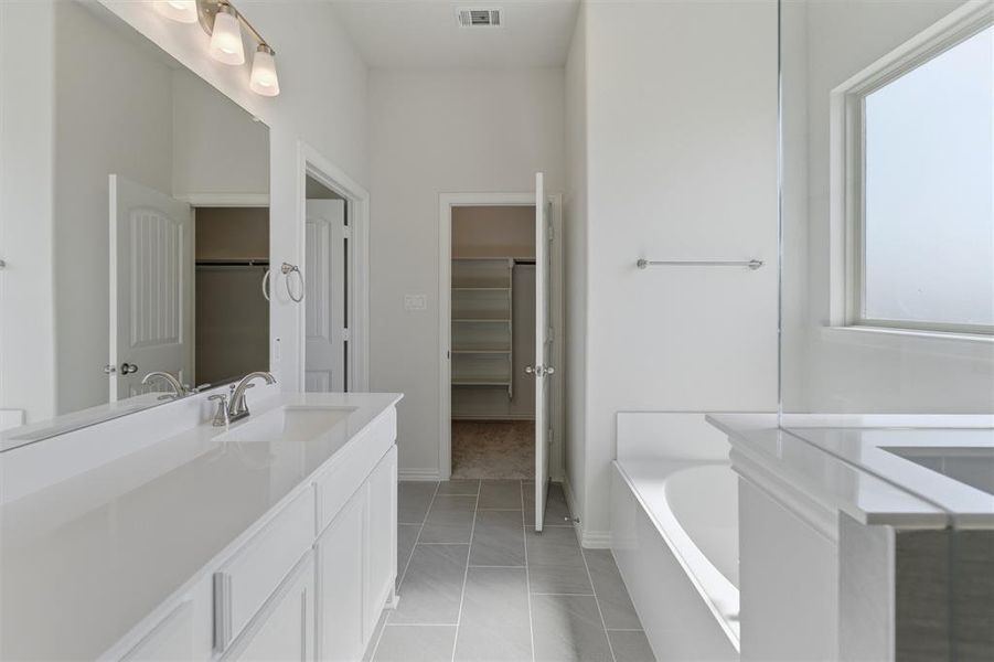 Bathroom featuring a double vanity with white cabinetry, integrated sinks, and polished chrome fixtures